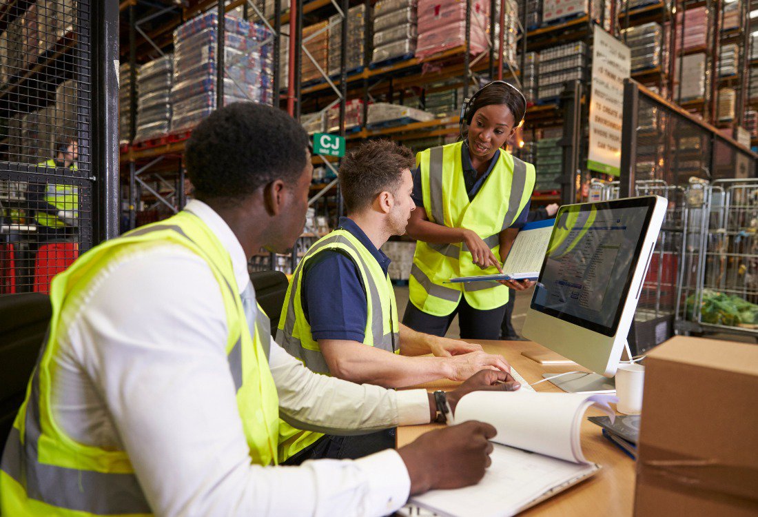 Team of professionals discussing warehouse logistics and supply chain operations in an on-site office, highlighting collaboration and challenges in supply chain maturity and process improvement.
